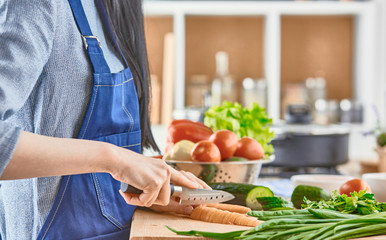 A young woman prepares food in the kitchen. Healthy food - vege