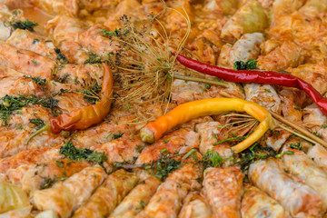 Close up of a freshly cooked large portion of sarmale, traditional Romanian cabbage rolls, with hot pepper and dill in display at a food market
