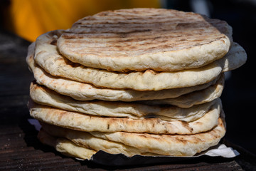 Home made pita bread displayed with different types of meat, for sale at a street food market