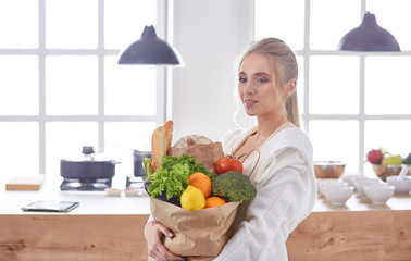 Obraz premium Young woman holding grocery shopping bag with vegetables Standi
