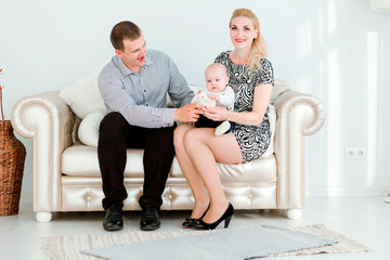 Obraz premium Family time. Dad and mom are sitting on the couch with their young son