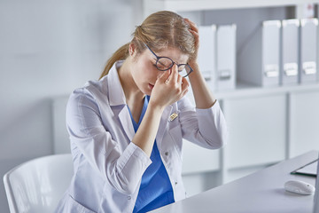 Young female doctor tired after working with computer