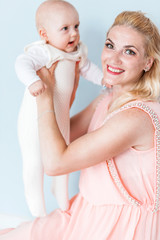 mom in a pink dress holds her little son in her arms and smiles