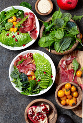 Low carbs bowl. Fresh salad with green spinach, rucola, avocado an ham serrano in white bowl, gray background, top view