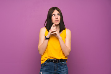 Young woman over isolated purple wall scheming something