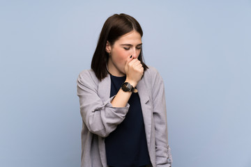 Young woman over isolated blue wall is suffering with cough and feeling bad