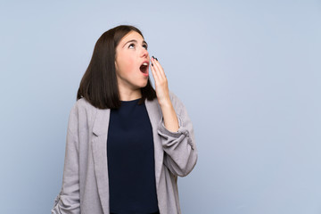 Young woman over isolated blue wall yawning and covering wide open mouth with hand