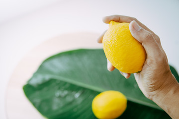 lemon held in the right hand and fresh banana leaves