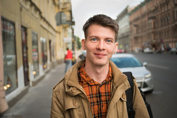 Portrait of handsome young man walking on the street and looking at camera.