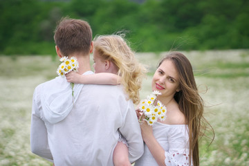 Happy family on big camomile mountain meadow.