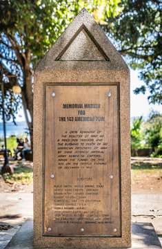 Puerto Princesa, Palawan, Philippines - March 3, 2019: Memorial marker at Plaza Quartel shows text on brown stone. Green foliage in back.