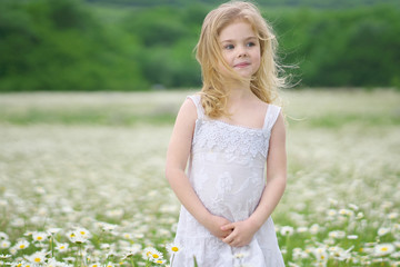 Fototapeta na wymiar Cute little girl in big camomile meadow