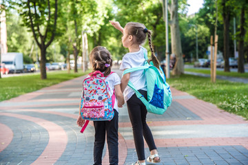 Back to school education concept with girl kids, elementary students, carrying backpacks going to class