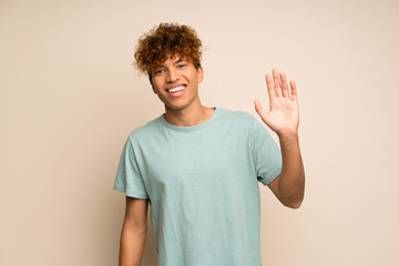 Fototapeta na wymiar African american man with green shirt saluting with hand with happy expression