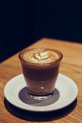 A cup of hot latte art on wooden table