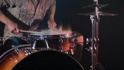 Fototapeta na wymiar musician playing drums with splashes, black background with beautiful soft light