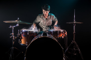 musician playing drums with splashes, black background with beautiful soft light