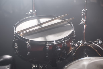 Close-up Drum set in a dark room against the backdrop of the spotlight. Atmospheric background symbol of playing rock or jazz drums.
