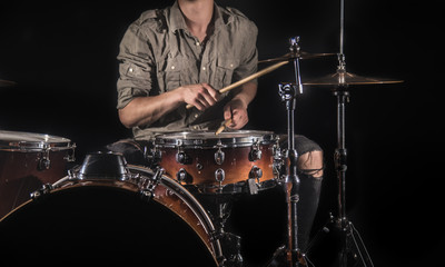 Fototapeta premium Professional drummer playing on drum set on stage on the black background