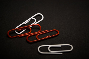 A set of multi-colored office paper clips of plastic are scattered on black monophonic background. 