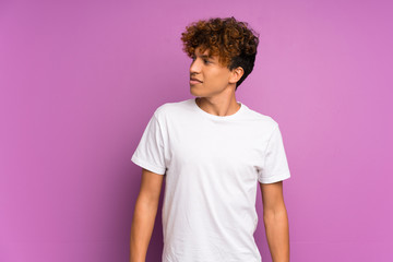 Young african american man over isolated purple wall making doubts gesture looking side