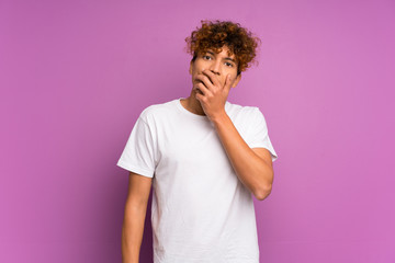 Young african american man over isolated purple wall surprised and shocked while looking right