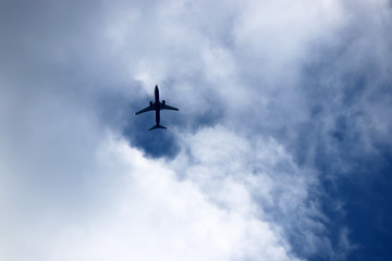 Airplane in the blue sky with white clouds. Commercial plane in a flight close up, bottom view