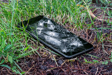 Broken phone with hole from bullet in grass_