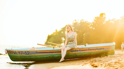 Young slim girl sitting on board rescue boat on shore