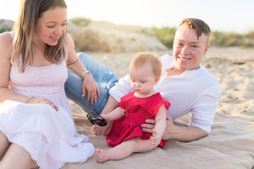 Fototapeta premium Family holiday near the sea. Father, mother and little daughter on beach.