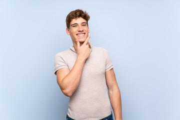 Handsome young man over isolated blue wall smiling