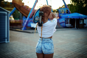 Girl holding skateboard in summer