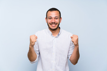 Fototapeta premium Colombian man over isolated blue wall celebrating a victory in winner position