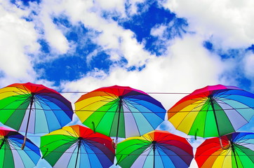 colorful rainbow bright umbrellas  street decoration against a blue sky with fluffy clouds