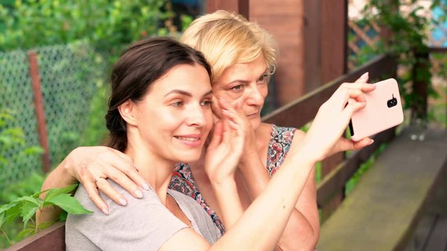 Happy daughter taking selfie photo with her mum on the porch in garden, 4K