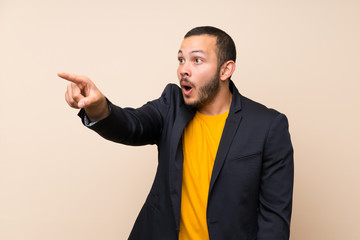 Colombian man over isolated background pointing away