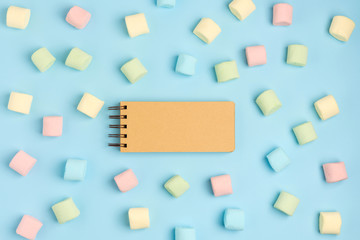 Blue paper background with marshmallow and notepad. Place for your text. Cozy sweet background