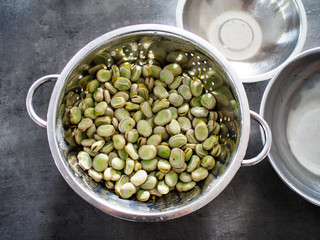 Broad beans in strainer on stone table