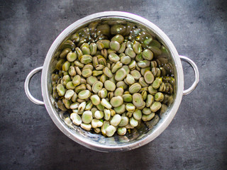 Broad beans in strainer on stone table