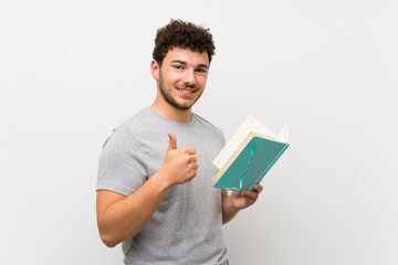 Man with curly hair over isolated wall holding and reading a book