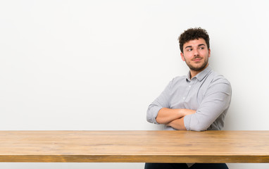 Young man with a table with arms crossed and happy