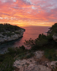 Sunrise with orange sky and water from a small bay in Mallorca, Spain. 