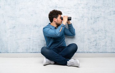 Young man sitting on the floor with black binoculars