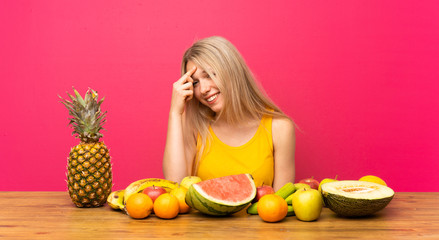 Young blonde woman with lots of fruits laughing