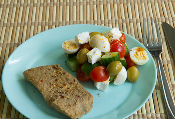 Piece of pork, tomato salad, cucumber, pickle cheese, olives, quail eggs