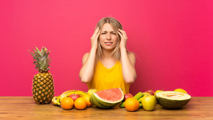 Young blonde woman with lots of fruits unhappy and frustrated with something. Negative facial expression
