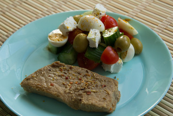 Piece of pork, tomato salad, cucumber, pickle cheese, olives, quail eggs