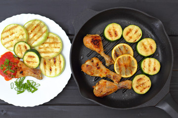 grilled chicken, tomato sauce and zucchini on a plate, black background