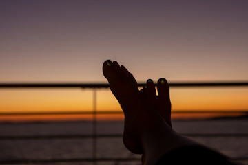 silhouette of feet relaxing on a ships rail