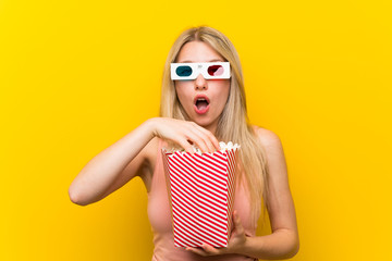 Young woman with popcorns over pink wall